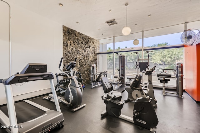 exercise room with a wall of windows and visible vents