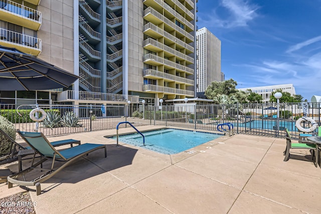 community pool with fence and a patio