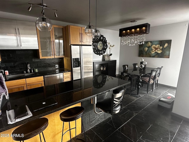 kitchen with appliances with stainless steel finishes, dark countertops, a sink, and a kitchen bar