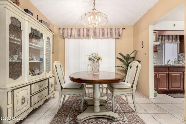 dining room featuring an inviting chandelier, light tile patterned flooring, vaulted ceiling, a textured ceiling, and baseboards