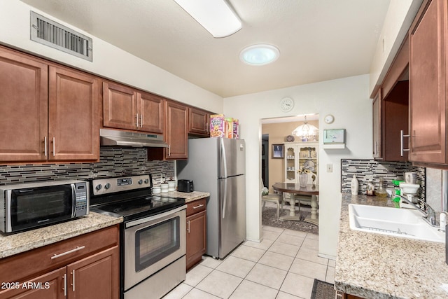 kitchen with light tile patterned floors, stainless steel appliances, visible vents, a sink, and under cabinet range hood