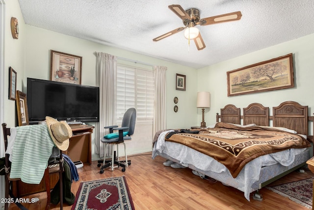 bedroom with light wood-type flooring, ceiling fan, and a textured ceiling