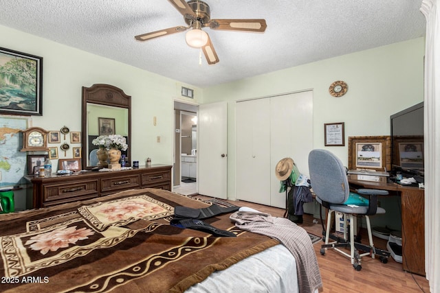 bedroom with light wood-style flooring, a textured ceiling, visible vents, and a closet