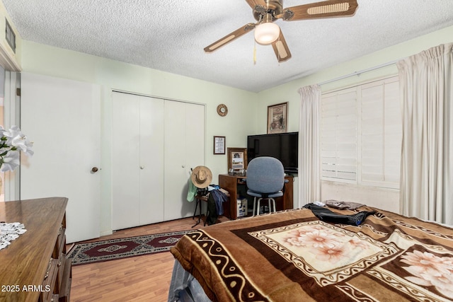 bedroom featuring a textured ceiling, ceiling fan, a closet, and wood finished floors