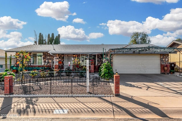 single story home with a garage, stone siding, a fenced front yard, and concrete driveway