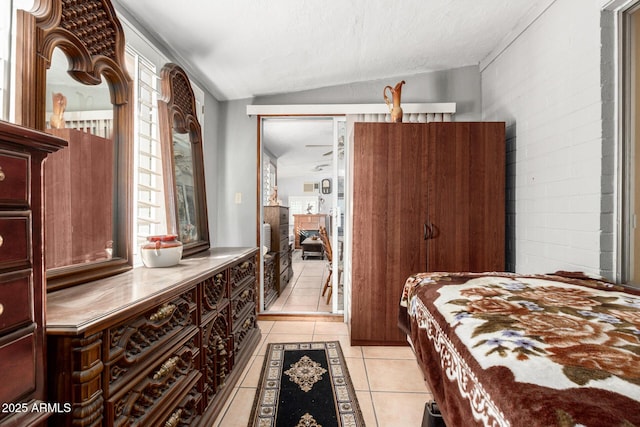 bedroom featuring lofted ceiling, a textured ceiling, and light tile patterned flooring