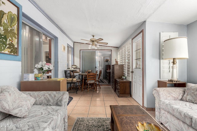 living area with a ceiling fan, light tile patterned flooring, and a textured ceiling