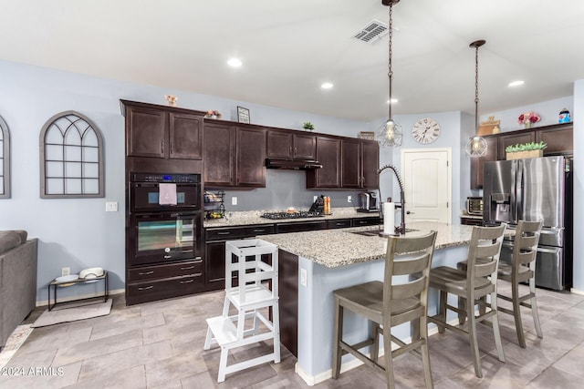 kitchen featuring pendant lighting, sink, black appliances, an island with sink, and a kitchen bar