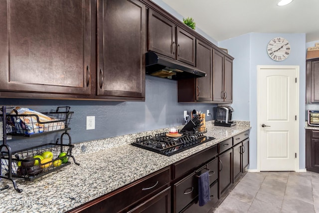 kitchen with light stone counters, dark brown cabinetry, black gas stovetop, and light tile patterned floors