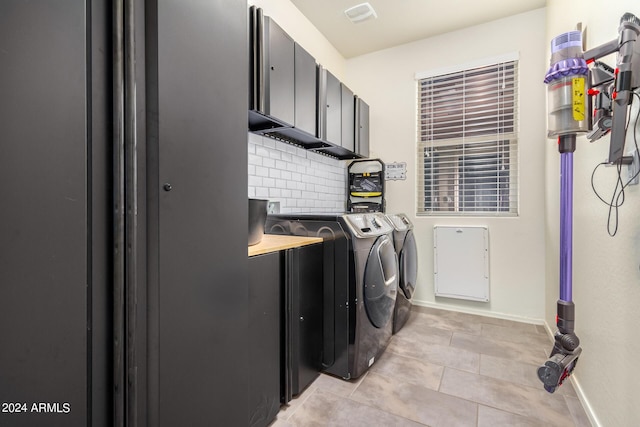 laundry area featuring light tile patterned floors, washer and clothes dryer, and cabinets