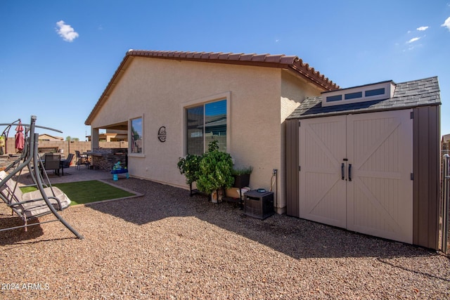 back of property with a shed and a patio