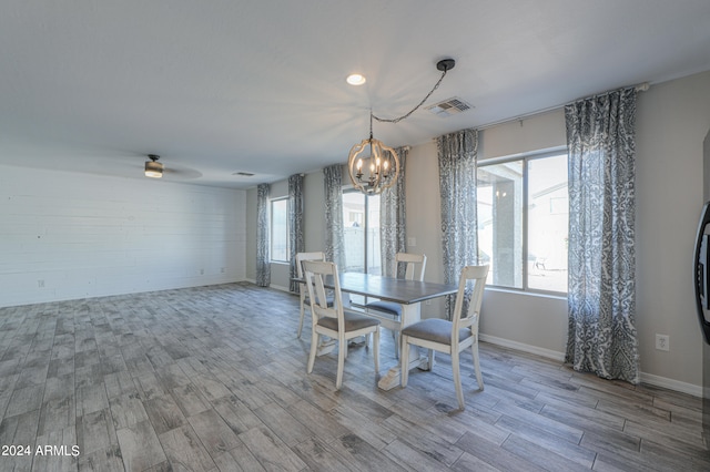 dining space with ceiling fan with notable chandelier and hardwood / wood-style flooring