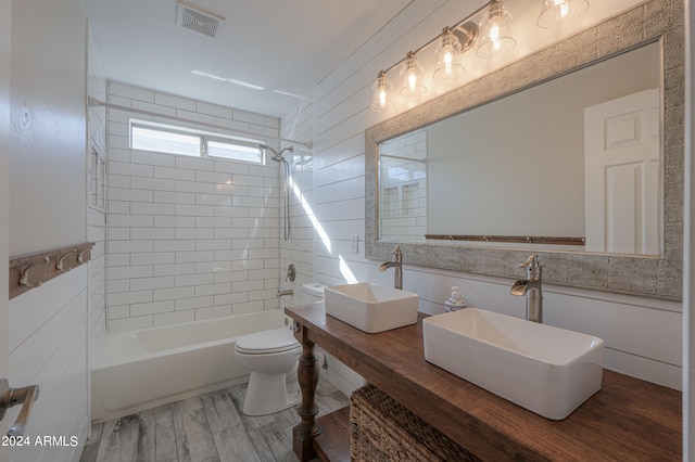 full bathroom featuring vanity, hardwood / wood-style flooring, tiled shower / bath combo, and toilet