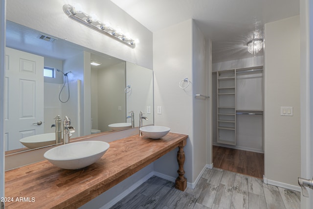 bathroom with wood-type flooring, vanity, walk in shower, and toilet