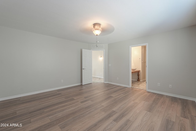 unfurnished bedroom featuring connected bathroom, ceiling fan, and hardwood / wood-style floors