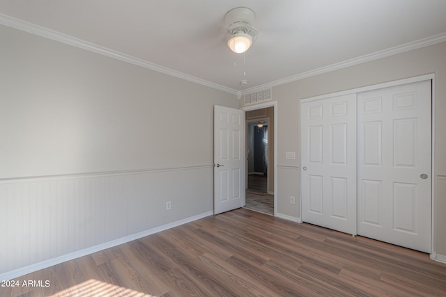 unfurnished bedroom with a closet, crown molding, and dark hardwood / wood-style flooring