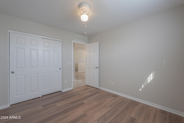 unfurnished bedroom with hardwood / wood-style floors, ceiling fan, and a closet