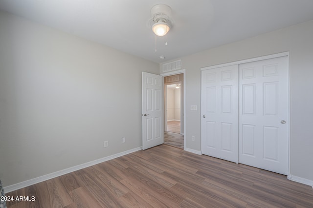 unfurnished bedroom featuring ceiling fan, a closet, and hardwood / wood-style flooring