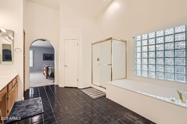 bathroom with vanity, separate shower and tub, and a towering ceiling