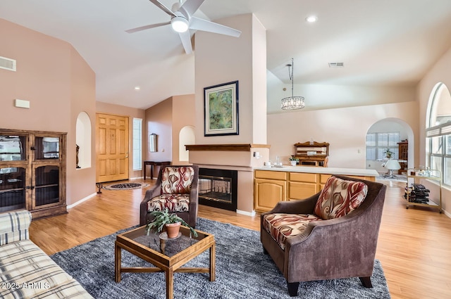 living room featuring a wealth of natural light, ceiling fan with notable chandelier, and light wood-type flooring