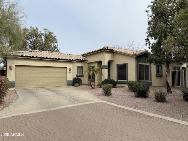 mediterranean / spanish-style house with driveway, a tiled roof, a garage, and stucco siding