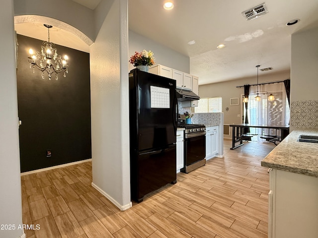 kitchen with stainless steel gas range oven, white cabinets, black fridge, decorative light fixtures, and a chandelier