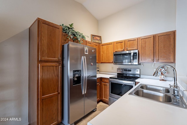 kitchen with sink, light tile patterned flooring, stainless steel appliances, and vaulted ceiling