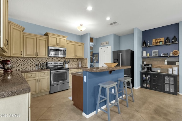 kitchen featuring tasteful backsplash, a breakfast bar area, a center island, light tile patterned floors, and stainless steel appliances