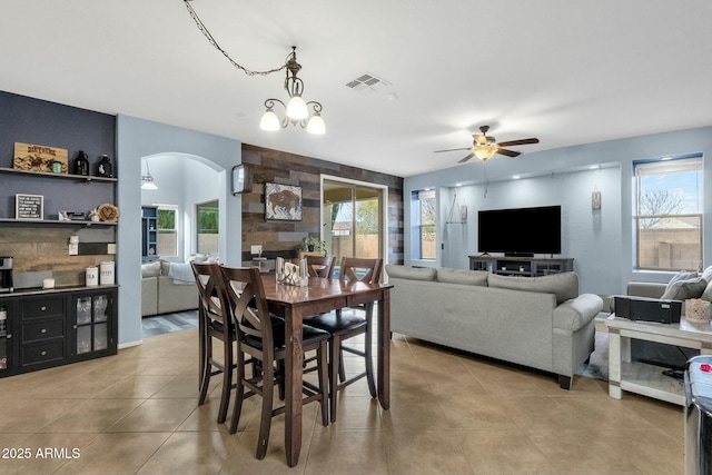 dining area featuring light tile patterned floors, ceiling fan with notable chandelier, and a fireplace