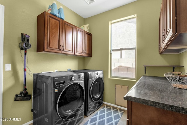 clothes washing area featuring cabinets and washer and clothes dryer