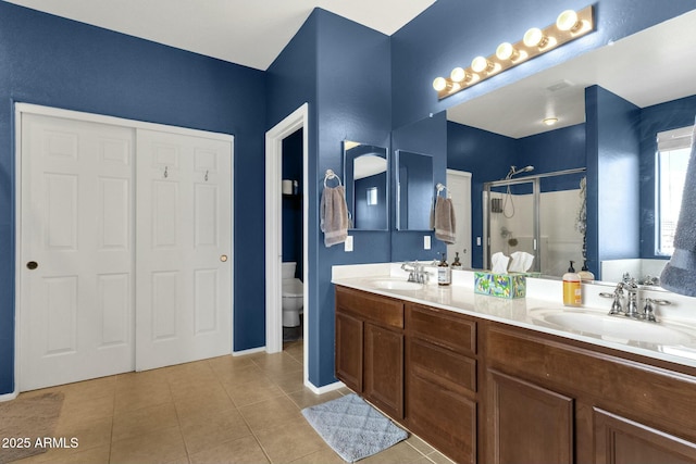 bathroom featuring vanity, toilet, tile patterned flooring, and a shower with door