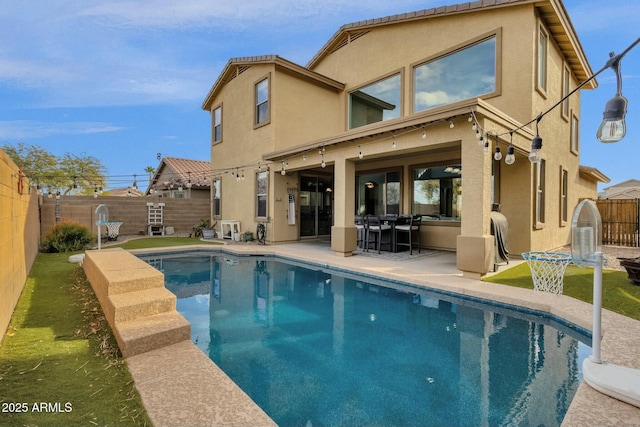 back of house with a fenced in pool and a patio