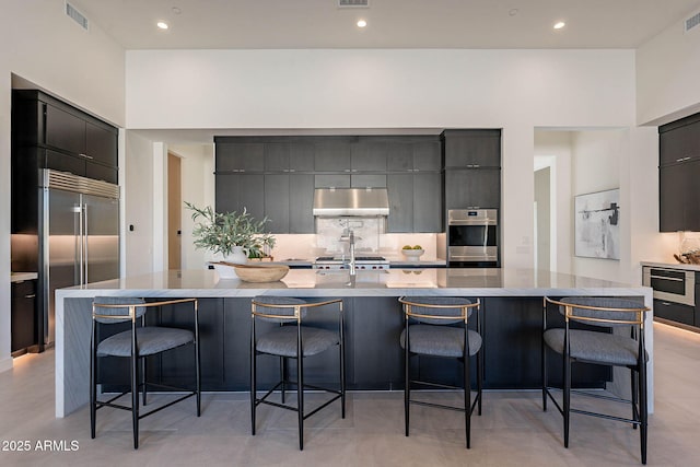 kitchen with a spacious island, stainless steel appliances, a breakfast bar, and tasteful backsplash