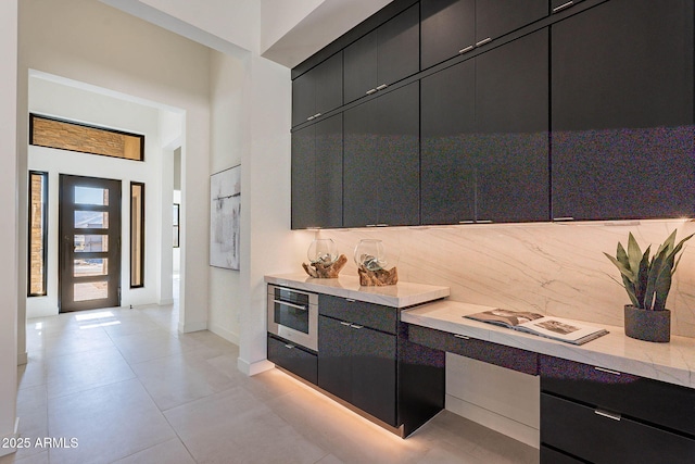 kitchen featuring tasteful backsplash, built in desk, light tile patterned floors, and oven