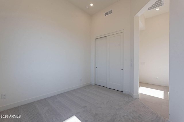 unfurnished bedroom featuring light carpet and a closet