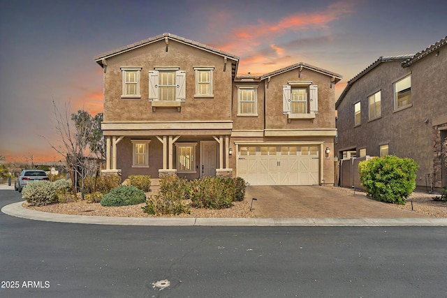 view of front of house featuring an attached garage, decorative driveway, and stucco siding