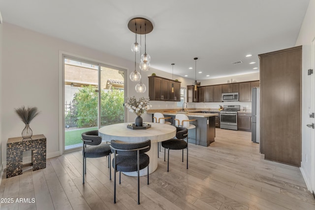 dining area featuring baseboards, light wood finished floors, visible vents, and recessed lighting