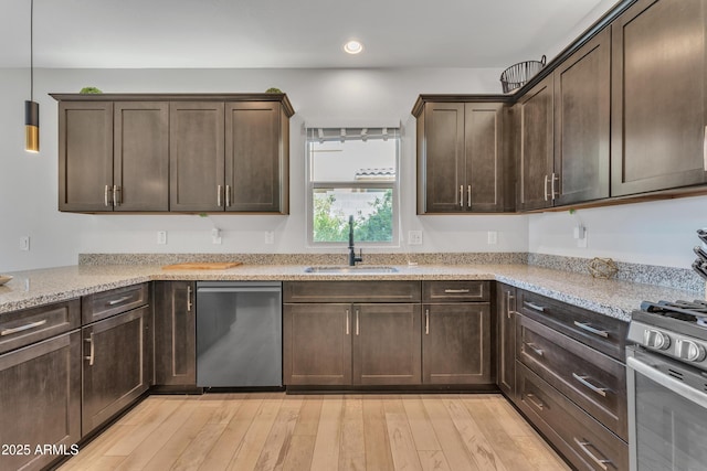 kitchen with dark brown cabinets, appliances with stainless steel finishes, a sink, and light wood-style flooring