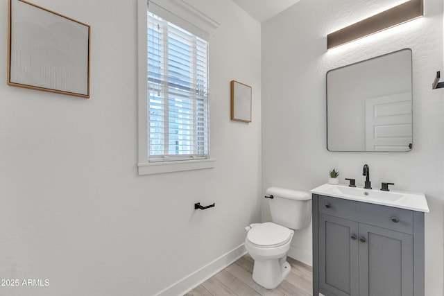 bathroom with toilet, baseboards, wood finished floors, and vanity