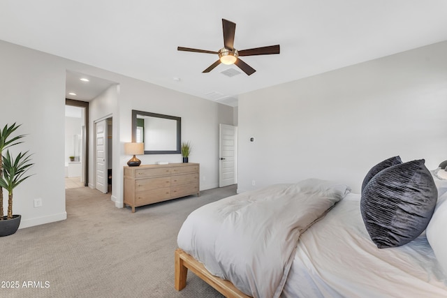 bedroom featuring light colored carpet, visible vents, ceiling fan, ensuite bath, and baseboards