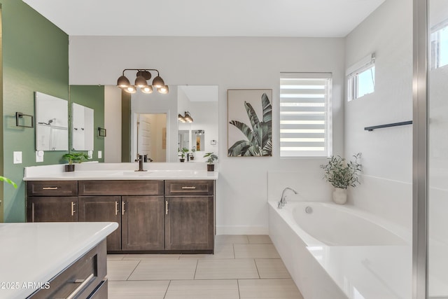 bathroom featuring a garden tub, vanity, baseboards, tile patterned floors, and an inviting chandelier