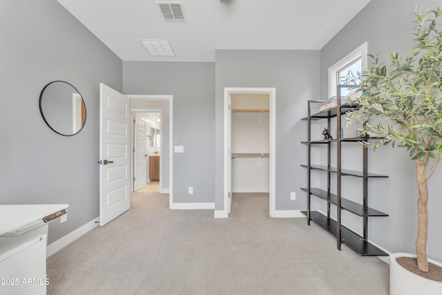 unfurnished bedroom with baseboards, a spacious closet, visible vents, and light colored carpet