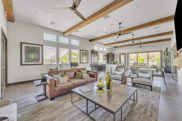 living area featuring light wood finished floors, beamed ceiling, visible vents, and baseboards