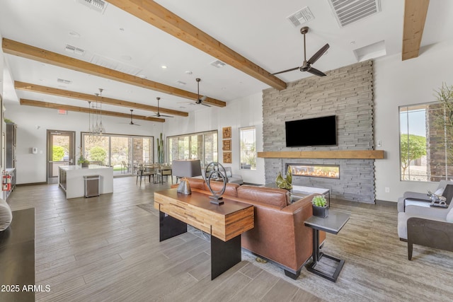 living room featuring a stone fireplace, visible vents, and a ceiling fan