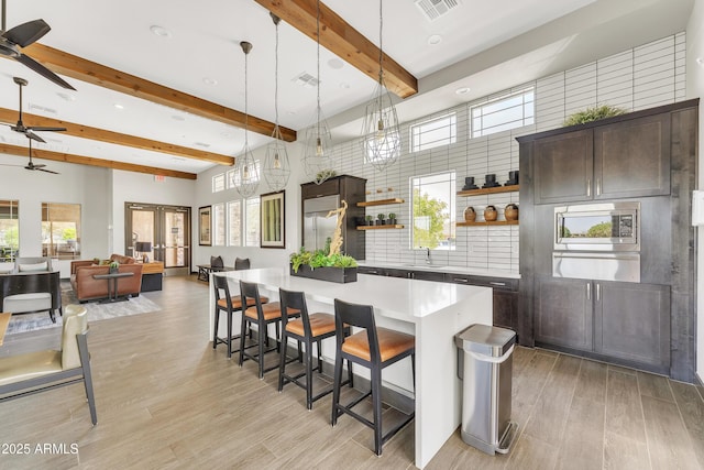 kitchen featuring french doors, open shelves, stainless steel microwave, visible vents, and dark brown cabinets