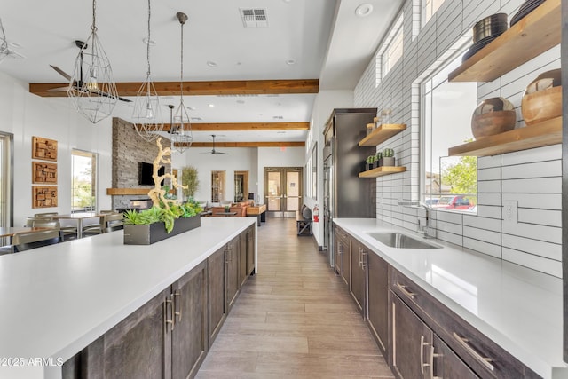 kitchen featuring a sink, dark brown cabinets, light countertops, open shelves, and tasteful backsplash