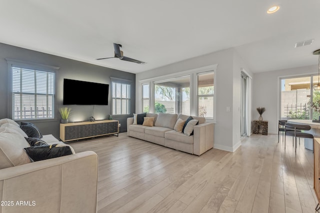 living room with light wood-style floors, baseboards, visible vents, and a ceiling fan