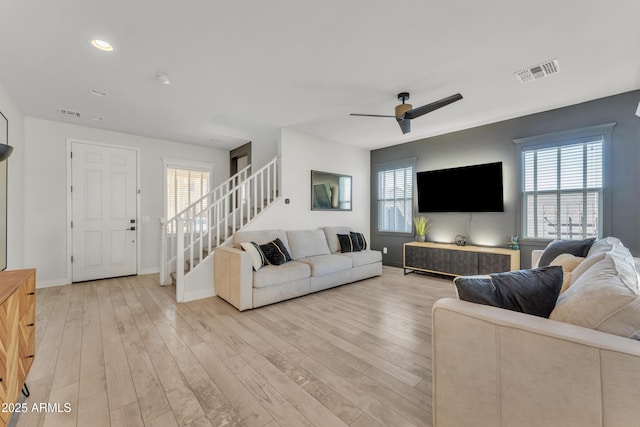 living room with light wood finished floors, stairs, visible vents, and a wealth of natural light