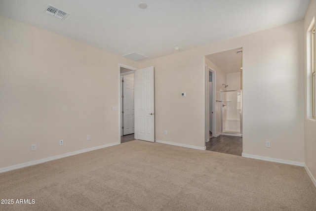 unfurnished bedroom featuring light carpet and ensuite bathroom