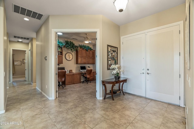 tiled foyer with built in desk and ceiling fan